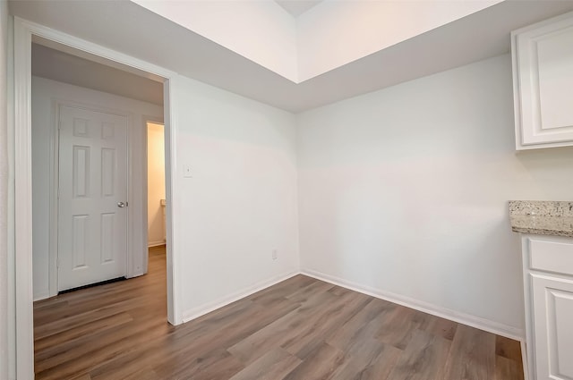 unfurnished dining area featuring wood finished floors and baseboards
