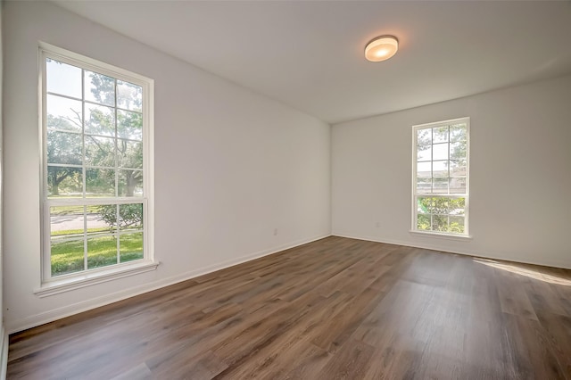 spare room with baseboards and dark wood-style flooring