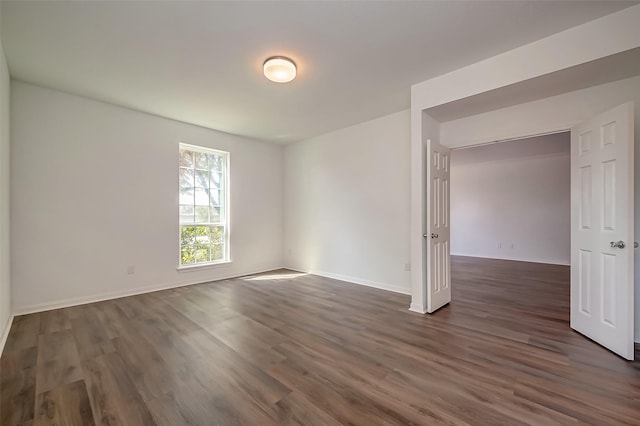 spare room featuring baseboards and dark wood-style flooring