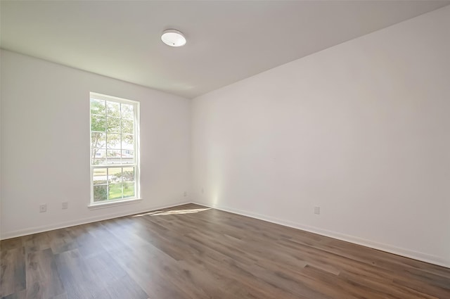 unfurnished room featuring baseboards and dark wood-style floors