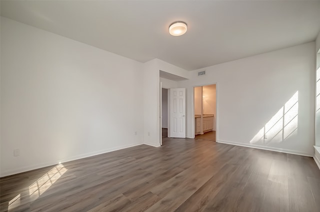 unfurnished bedroom with a closet, a walk in closet, and dark hardwood / wood-style floors