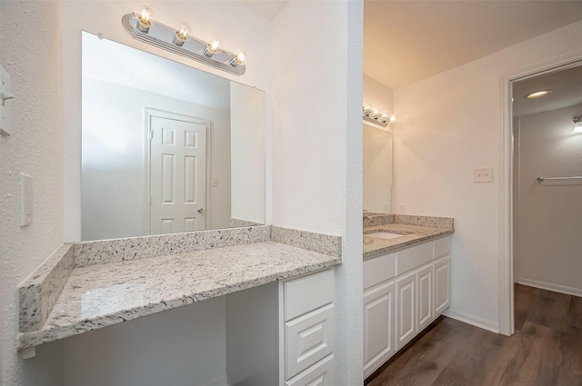 bathroom featuring baseboards, wood finished floors, and vanity