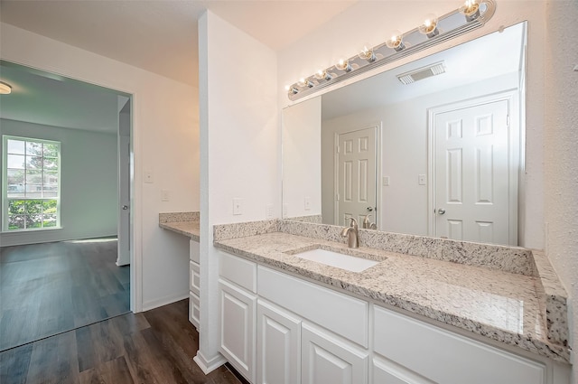 bathroom featuring baseboards, wood finished floors, visible vents, and vanity