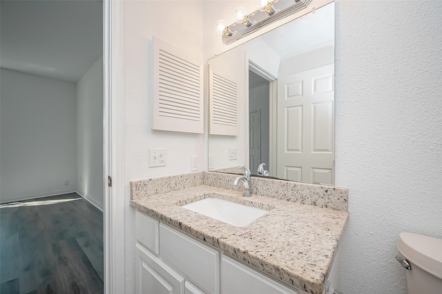 bathroom with hardwood / wood-style floors, vanity, and toilet