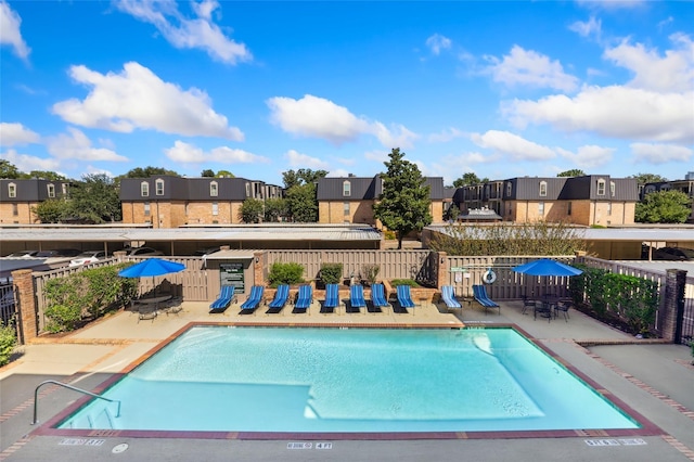 community pool featuring a residential view, a patio area, and fence