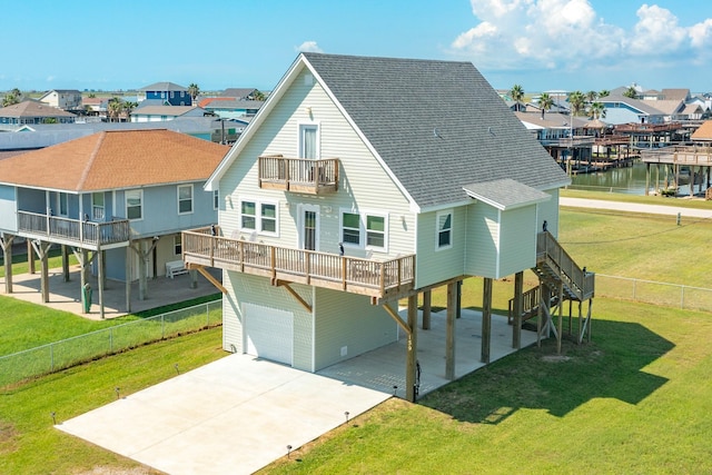 rear view of house with a water view, a balcony, a garage, and a yard