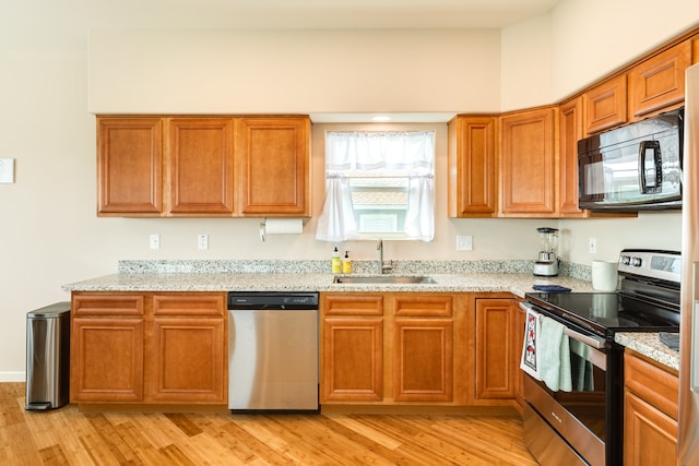 kitchen featuring light hardwood / wood-style flooring, stainless steel appliances, light stone counters, and sink