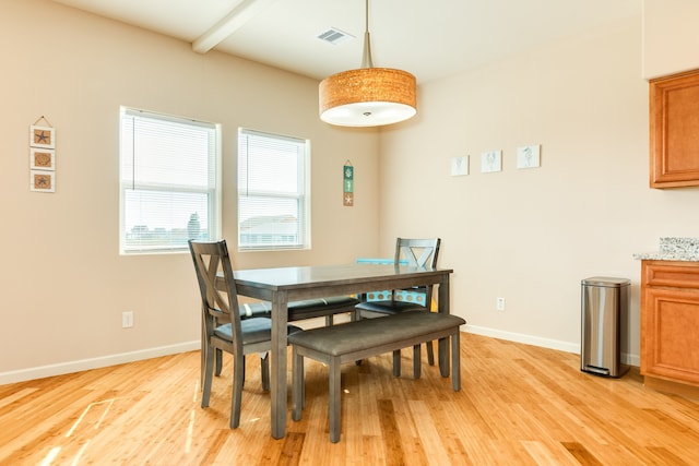 dining room with light hardwood / wood-style floors and beamed ceiling