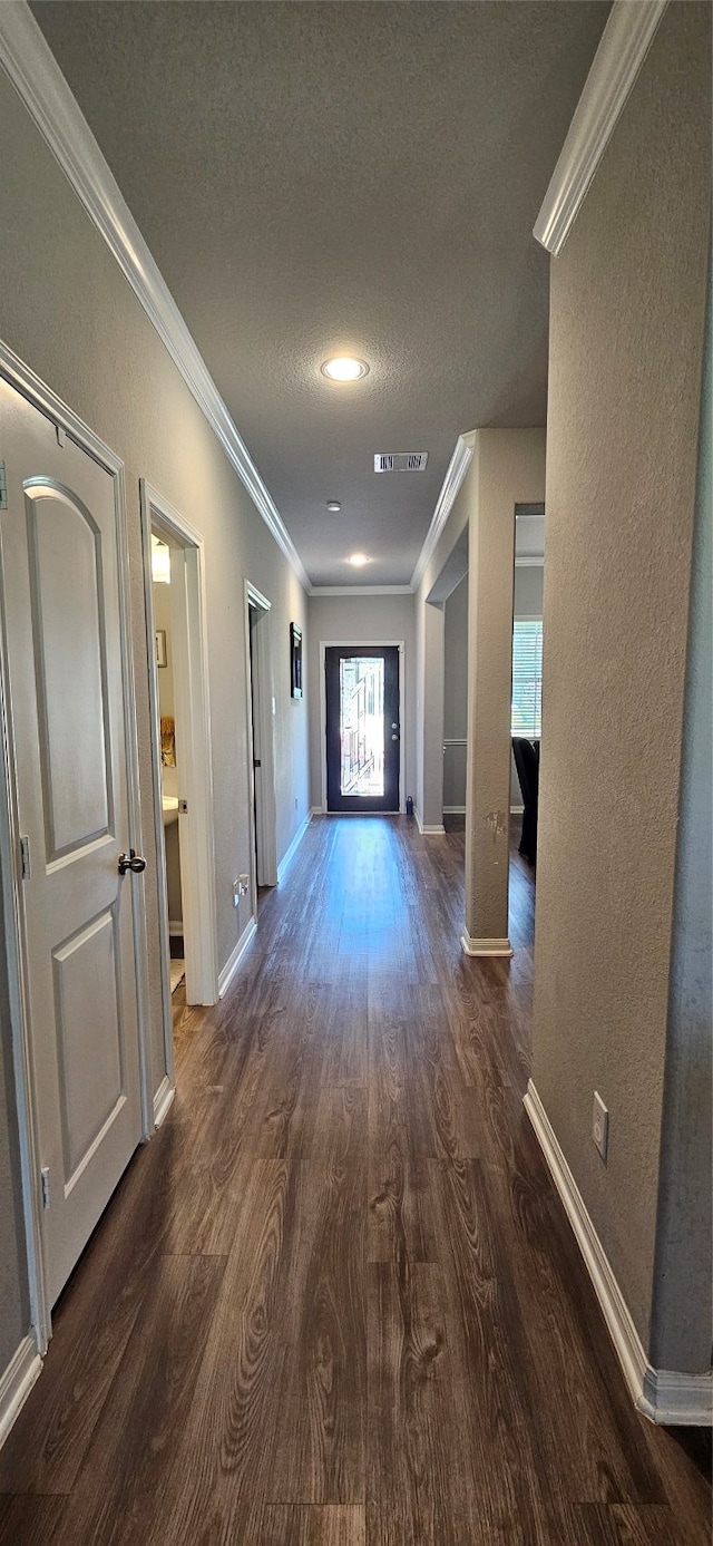 hallway with a textured ceiling, crown molding, and dark hardwood / wood-style floors