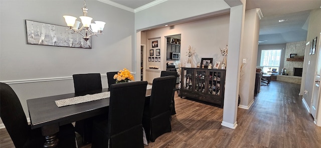 dining space with ornamental molding, a chandelier, a fireplace, and dark hardwood / wood-style flooring