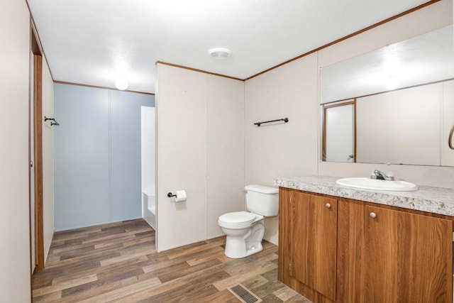 bathroom featuring wood-type flooring, vanity, toilet, and ornamental molding