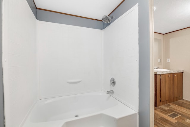 bathroom featuring vanity, hardwood / wood-style floors, washtub / shower combination, and crown molding