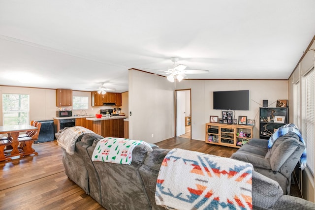 living room with ornamental molding, wood-type flooring, and ceiling fan