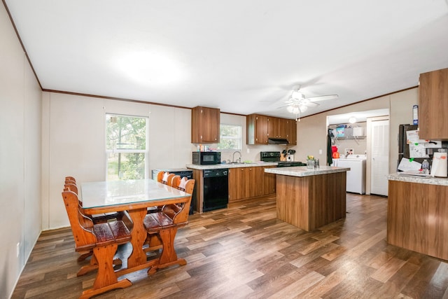 kitchen with wood-type flooring, washer / clothes dryer, a kitchen island, black appliances, and ceiling fan