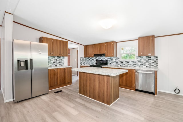 kitchen with appliances with stainless steel finishes, light hardwood / wood-style floors, backsplash, a kitchen island, and crown molding