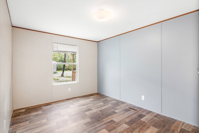 empty room featuring ornamental molding and hardwood / wood-style floors