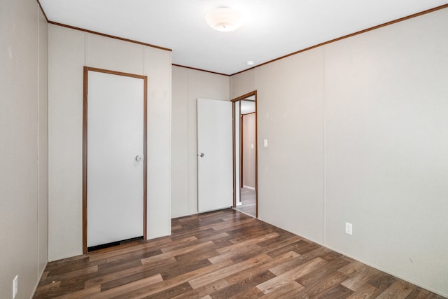 unfurnished bedroom with crown molding and dark hardwood / wood-style flooring