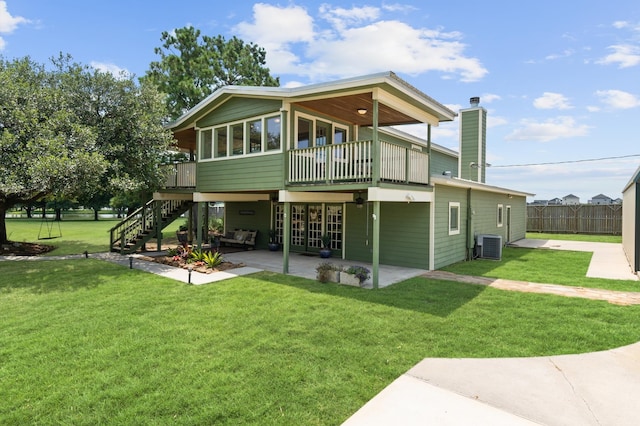 rear view of property with a sunroom, a lawn, a patio area, and central air condition unit