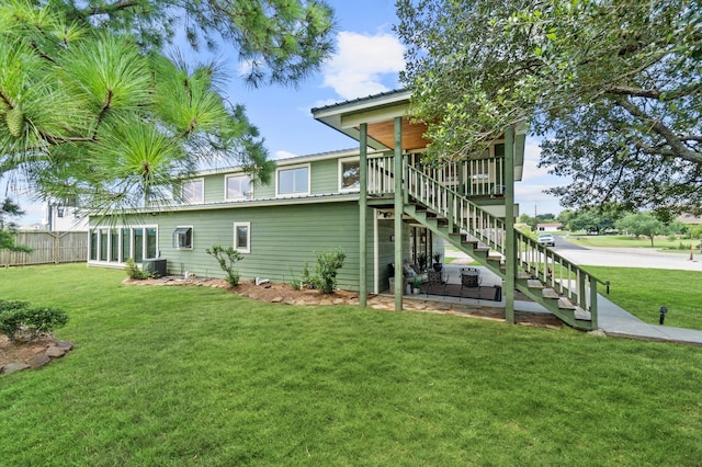 rear view of house featuring a lawn and central AC unit