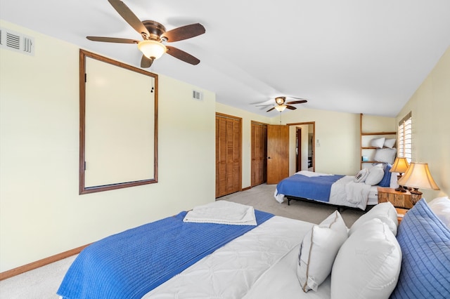 bedroom featuring lofted ceiling, ceiling fan, light colored carpet, and multiple closets