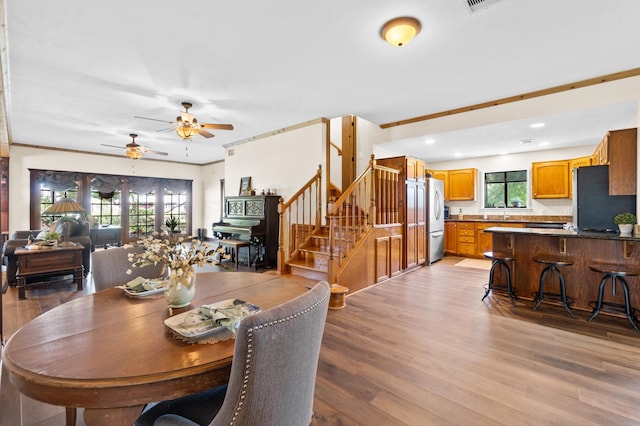 dining area with ornamental molding, sink, ceiling fan, and light hardwood / wood-style flooring