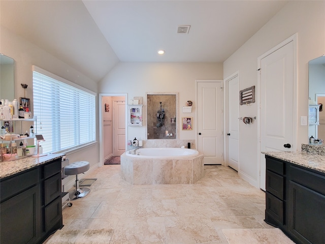 bathroom with vanity, a relaxing tiled tub, and vaulted ceiling