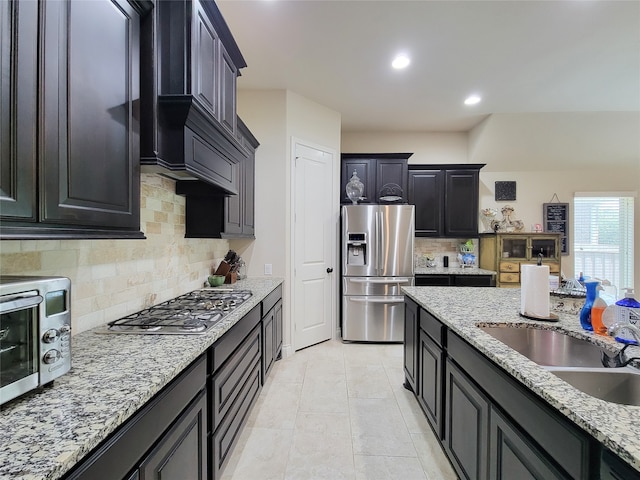 kitchen featuring light stone counters, light tile patterned floors, sink, backsplash, and stainless steel appliances