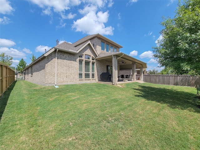 back of house with ceiling fan, a lawn, and a patio