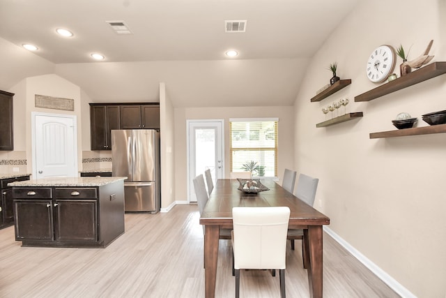 dining space featuring vaulted ceiling and light hardwood / wood-style floors