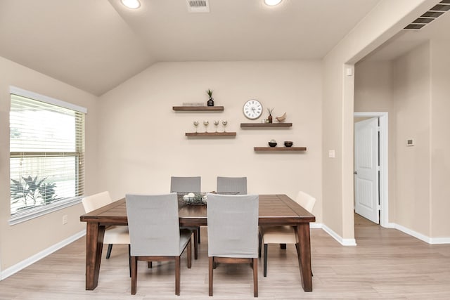 dining area with light wood-type flooring and vaulted ceiling