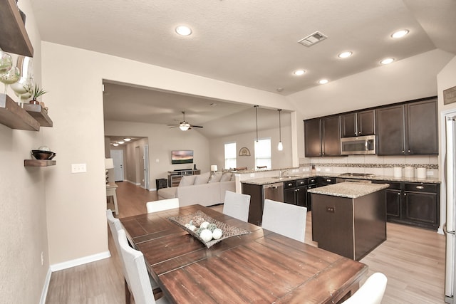 dining space featuring lofted ceiling, sink, ceiling fan, and light hardwood / wood-style flooring