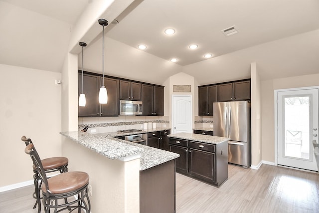 kitchen featuring kitchen peninsula, pendant lighting, stainless steel appliances, lofted ceiling, and light hardwood / wood-style flooring