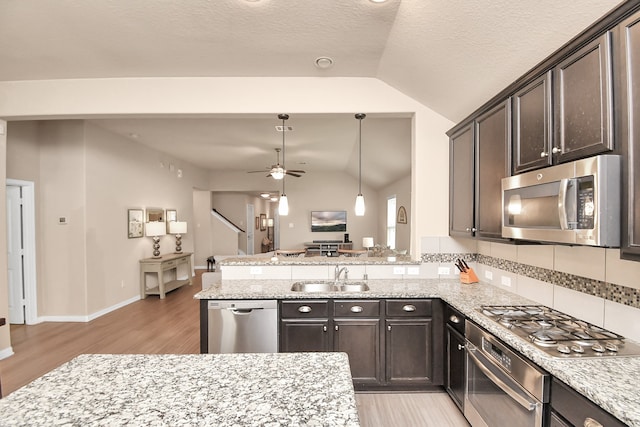 kitchen featuring light hardwood / wood-style floors, vaulted ceiling, stainless steel appliances, ceiling fan, and sink