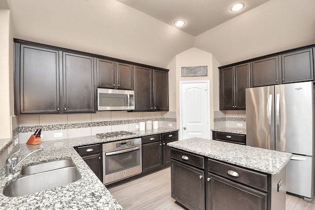 kitchen featuring appliances with stainless steel finishes, vaulted ceiling, sink, and tasteful backsplash