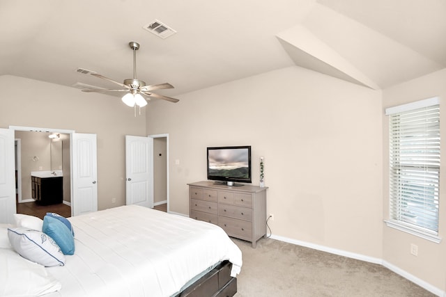 bedroom featuring light carpet, connected bathroom, lofted ceiling, and ceiling fan