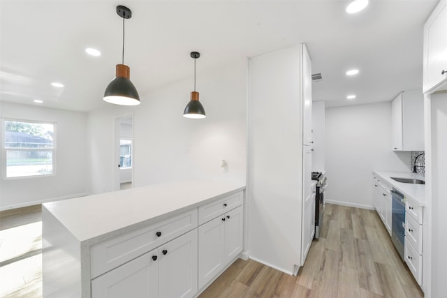 kitchen with pendant lighting, sink, white cabinets, light hardwood / wood-style flooring, and appliances with stainless steel finishes