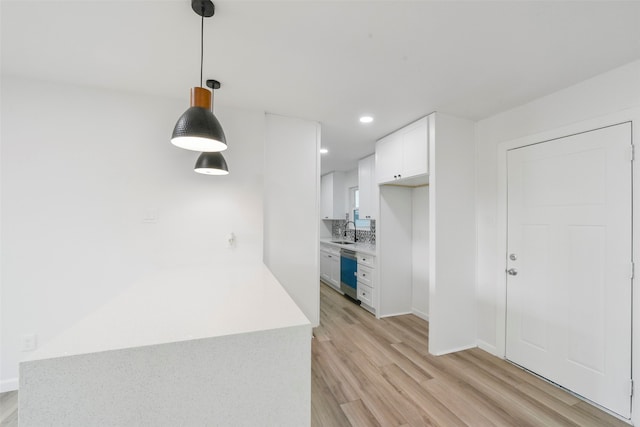 kitchen featuring white cabinets, pendant lighting, sink, dishwasher, and light hardwood / wood-style floors