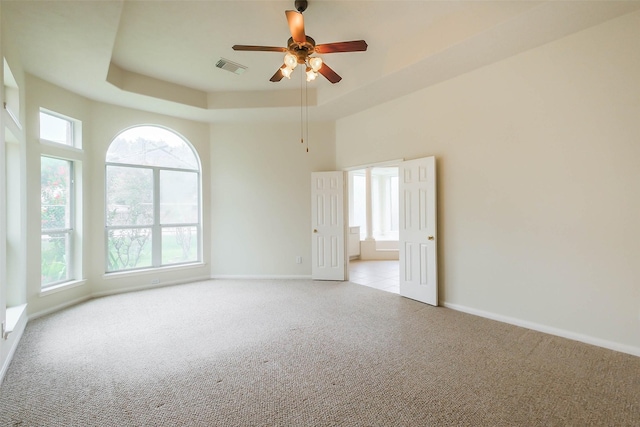 empty room with baseboards, visible vents, a ceiling fan, and carpet flooring