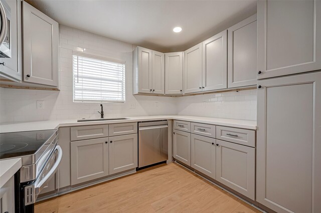 kitchen featuring stainless steel appliances, gray cabinets, backsplash, and light hardwood / wood-style floors