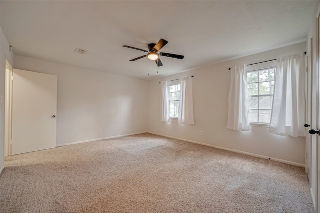 carpeted spare room with ceiling fan and plenty of natural light