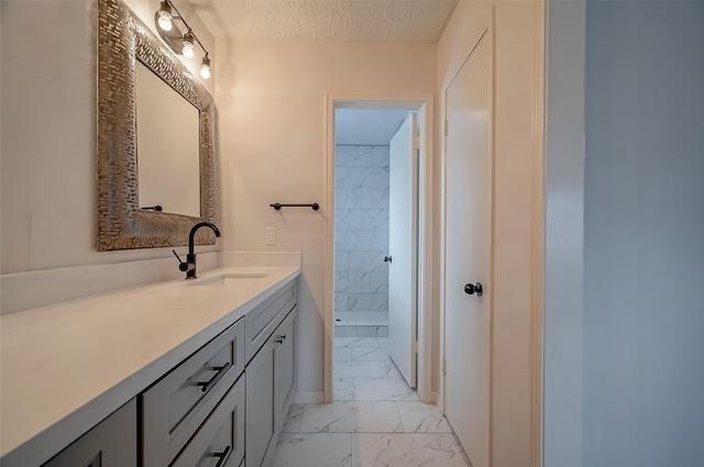 bathroom with vanity, a textured ceiling, and tiled shower