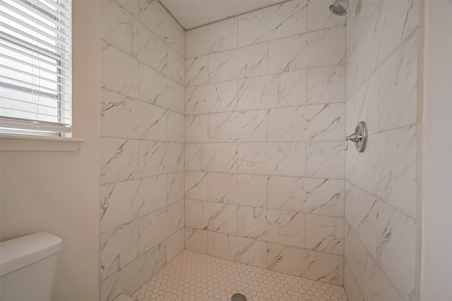 bathroom with a tile shower and toilet