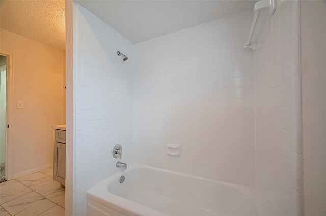 bathroom with vanity, a textured ceiling, and tiled shower / bath