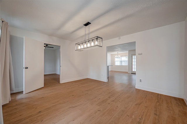 unfurnished dining area featuring an inviting chandelier and light hardwood / wood-style flooring