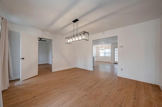 unfurnished dining area with a chandelier, light hardwood / wood-style flooring, and a textured ceiling