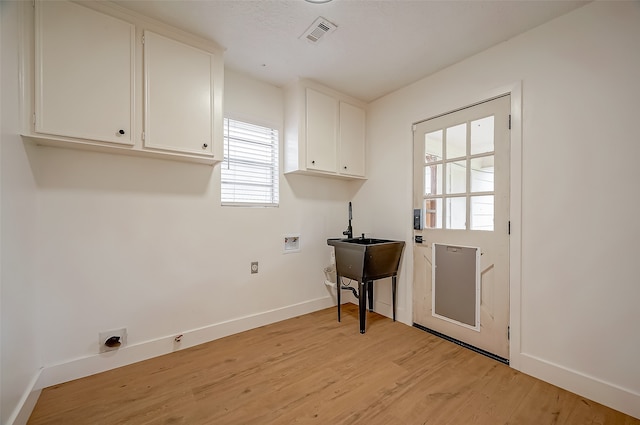 washroom with cabinets, washer hookup, and light hardwood / wood-style flooring