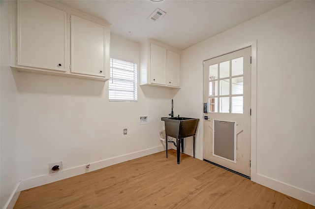 washroom with cabinets, light hardwood / wood-style floors, and hookup for a washing machine