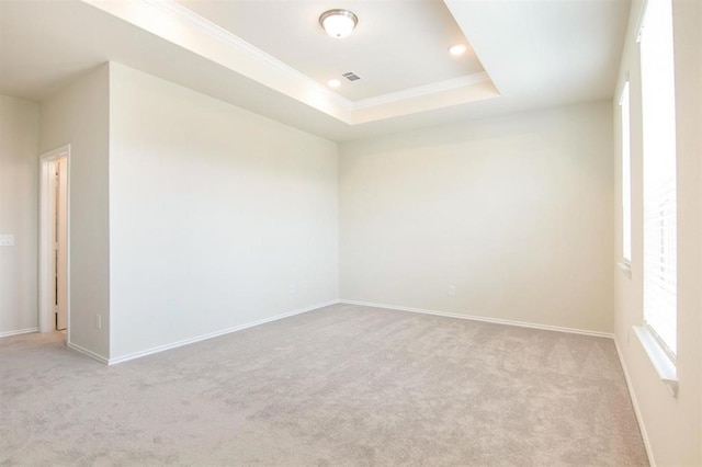 carpeted spare room featuring a raised ceiling and crown molding