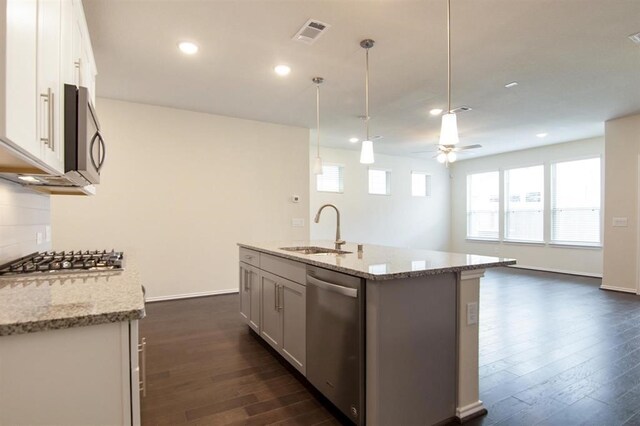 kitchen with appliances with stainless steel finishes, light stone countertops, sink, and white cabinets