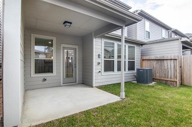 view of exterior entry with a yard, a patio area, and central air condition unit